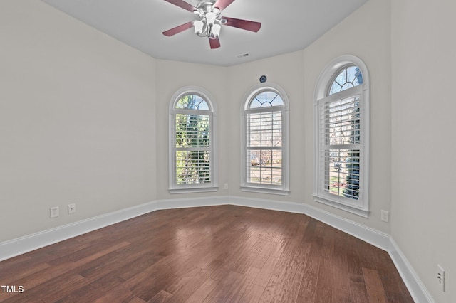 empty room featuring visible vents, wood finished floors, baseboards, and ceiling fan