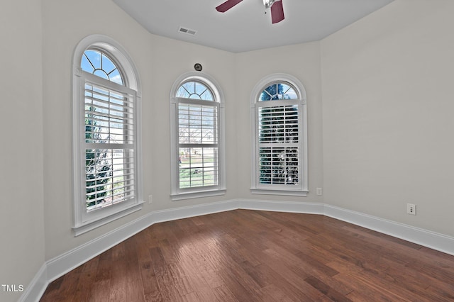 unfurnished room featuring visible vents, ceiling fan, baseboards, and dark wood-style flooring