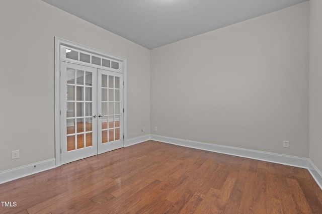 spare room featuring french doors, baseboards, and wood finished floors