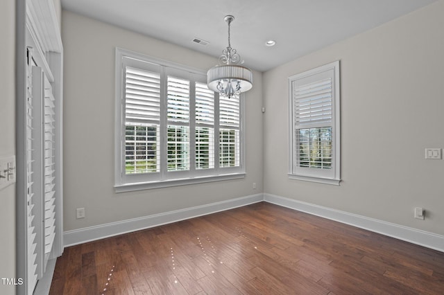 unfurnished dining area with visible vents, baseboards, a notable chandelier, and hardwood / wood-style flooring