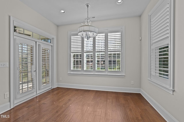 unfurnished dining area with dark wood-style floors, a notable chandelier, recessed lighting, and baseboards