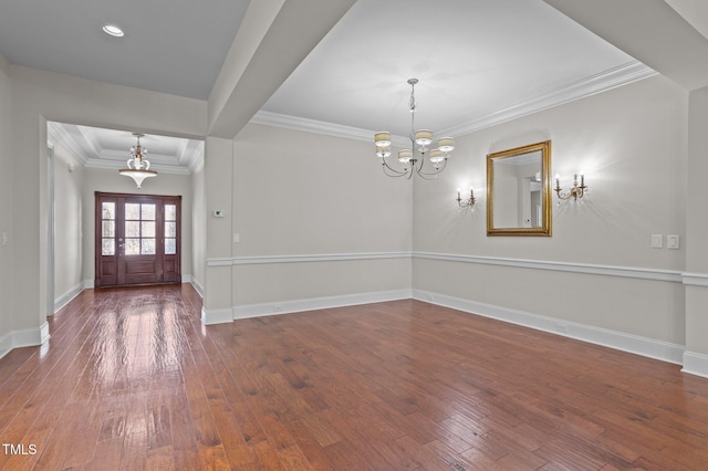 entrance foyer featuring baseboards, a notable chandelier, hardwood / wood-style floors, and crown molding