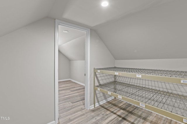 additional living space with baseboards, lofted ceiling, and light wood-style floors