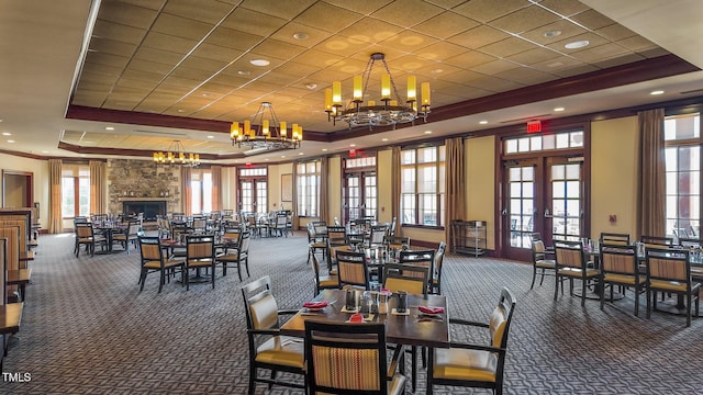 dining space with a tray ceiling, ornamental molding, carpet floors, french doors, and a fireplace