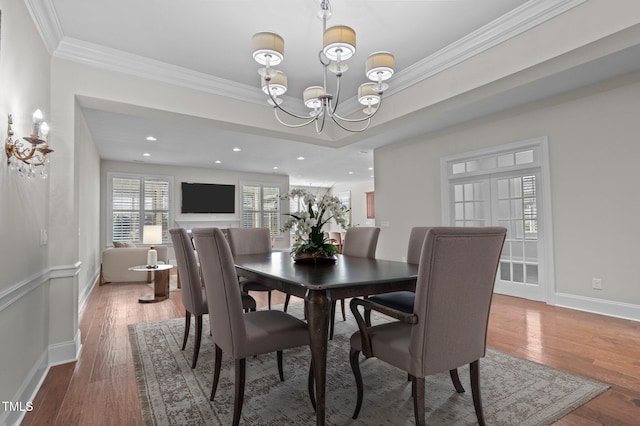 dining area featuring baseboards, wood finished floors, a chandelier, and crown molding