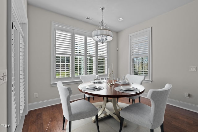 dining space featuring a notable chandelier, wood finished floors, visible vents, and baseboards