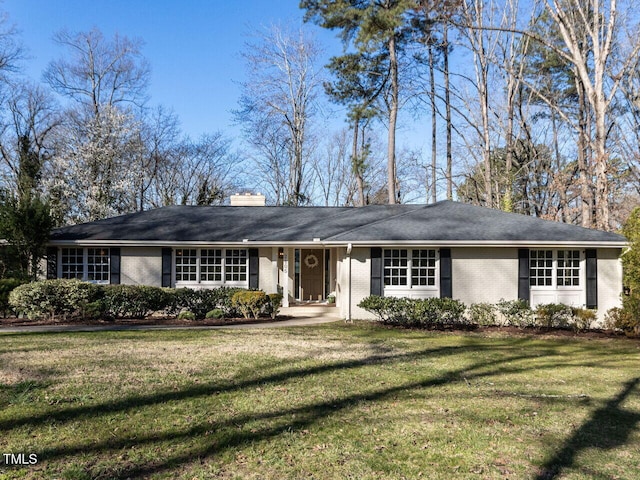 ranch-style home with brick siding, a chimney, and a front lawn