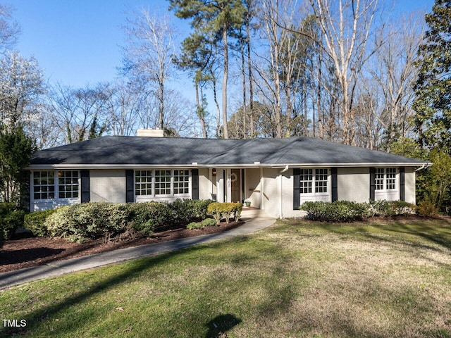 ranch-style home featuring brick siding, a chimney, and a front lawn