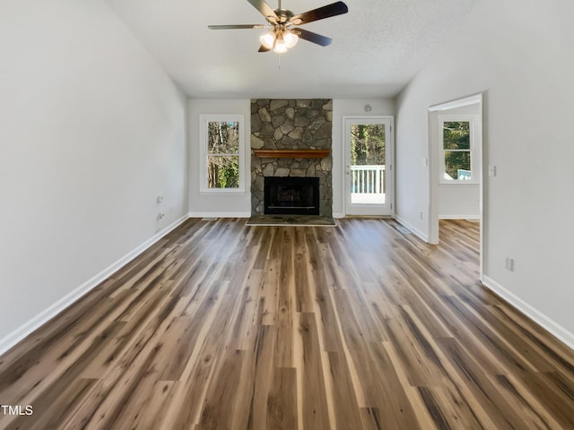 unfurnished living room with a wealth of natural light, a fireplace, lofted ceiling, and wood finished floors