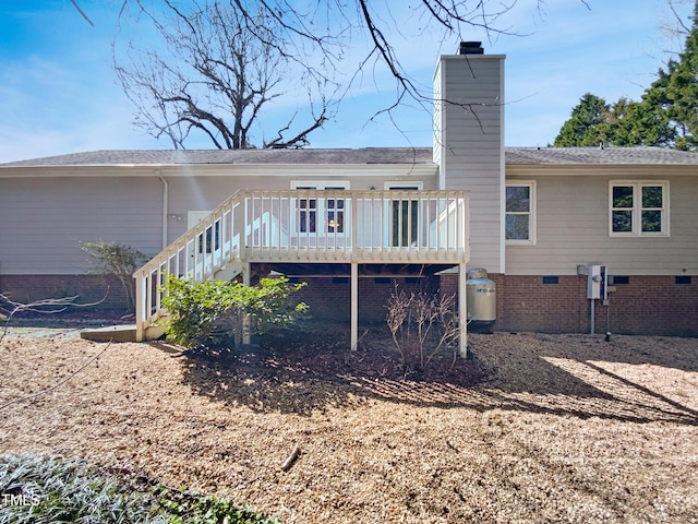 rear view of house with a deck, stairway, crawl space, and a chimney