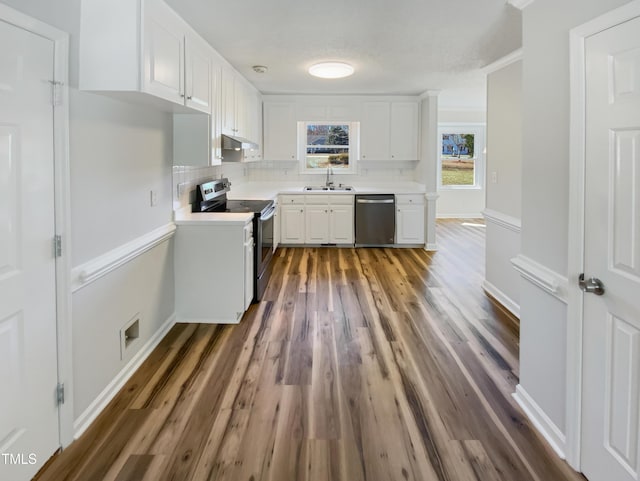 kitchen with light countertops, decorative backsplash, appliances with stainless steel finishes, white cabinets, and a sink