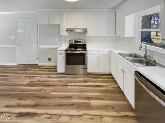 kitchen with white cabinets, a sink, stainless steel appliances, under cabinet range hood, and backsplash