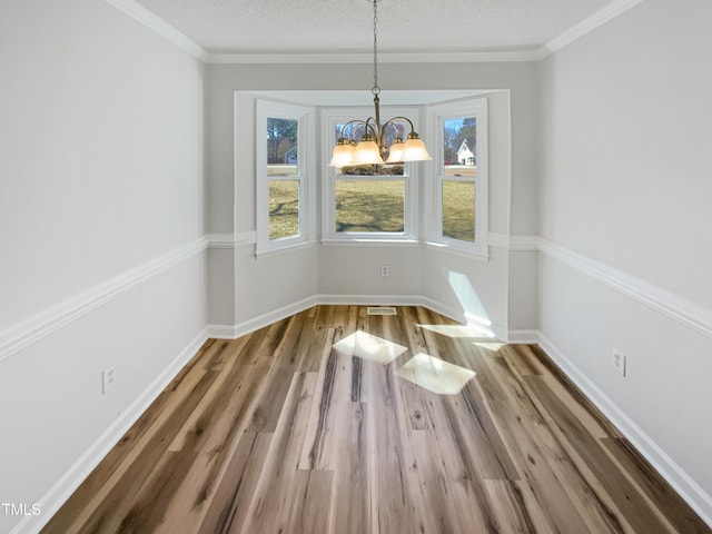 unfurnished dining area with a textured ceiling, baseboards, and wood finished floors