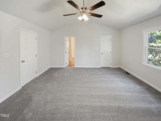 interior space with baseboards, connected bathroom, lofted ceiling, ceiling fan, and carpet floors