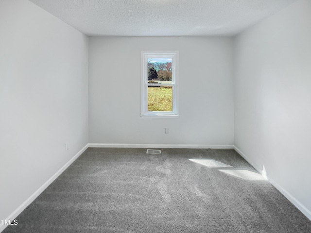 carpeted spare room featuring visible vents, a textured ceiling, and baseboards