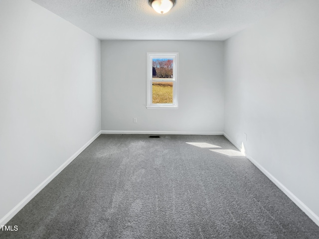 carpeted spare room with visible vents, a textured ceiling, and baseboards