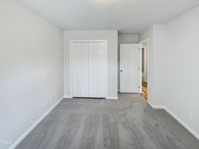 unfurnished bedroom with carpet, a textured ceiling, baseboards, and a closet