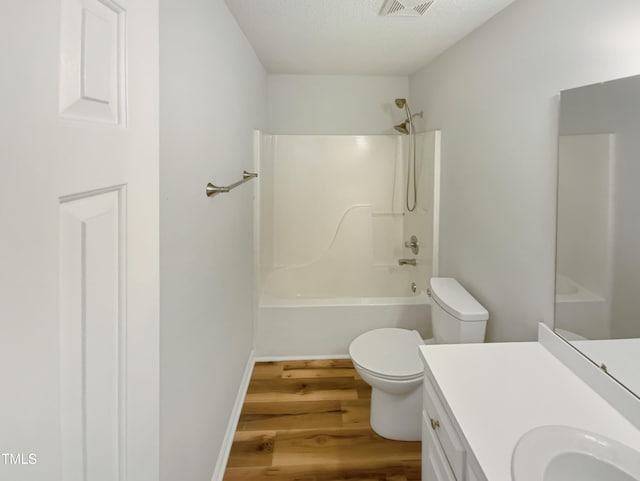 bathroom featuring visible vents, toilet, wood finished floors, tub / shower combination, and vanity