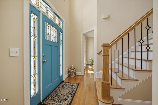 foyer entrance with stairs, wood finished floors, a wealth of natural light, and baseboards