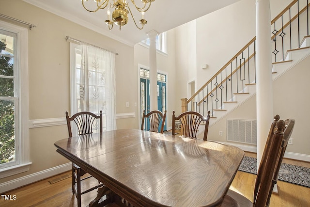 dining room featuring a healthy amount of sunlight, visible vents, stairway, and wood finished floors