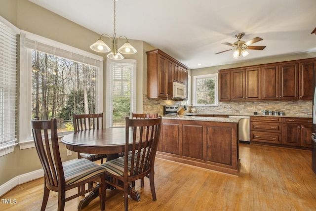 kitchen featuring light wood-style floors, baseboards, stainless steel appliances, and backsplash