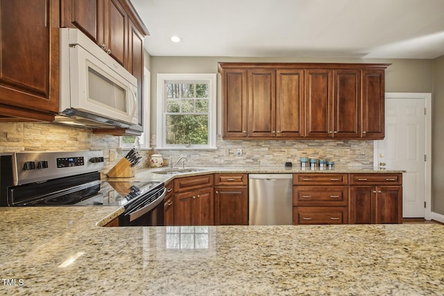 kitchen featuring tasteful backsplash, appliances with stainless steel finishes, light stone counters, and a sink