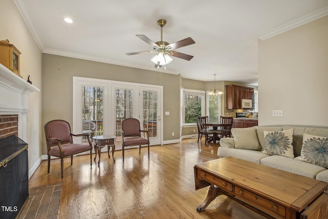 living area with ornamental molding, a fireplace, baseboards, and wood finished floors