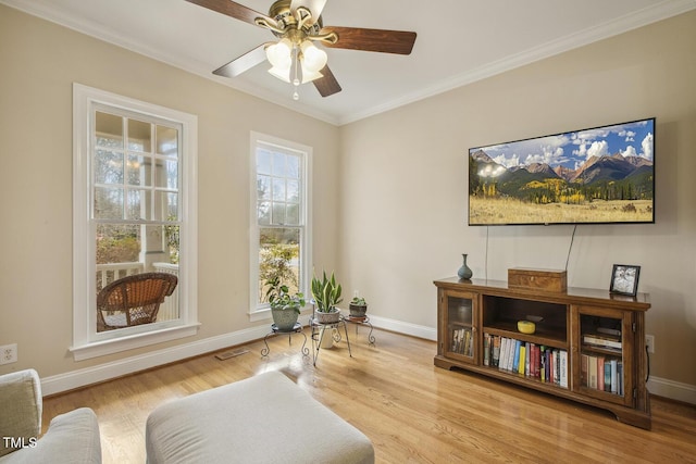 living area with visible vents, baseboards, a ceiling fan, wood finished floors, and crown molding