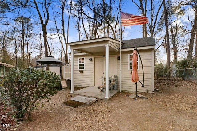 view of front of home featuring an outbuilding, a storage shed, a shingled roof, and fence