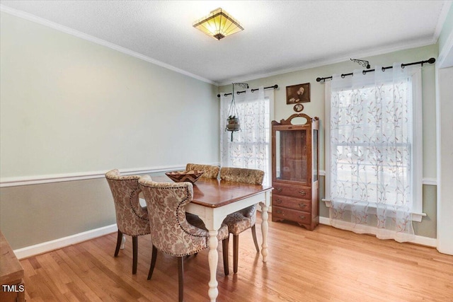 dining space with baseboards, light wood finished floors, a textured ceiling, and crown molding