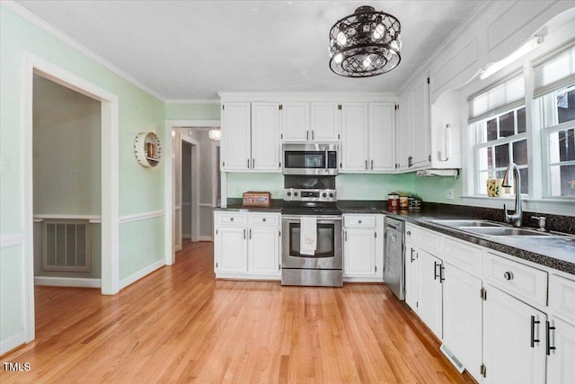 kitchen featuring a sink, visible vents, appliances with stainless steel finishes, dark countertops, and crown molding