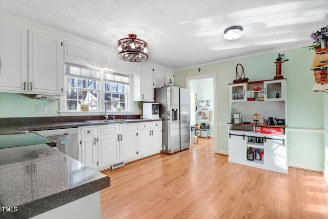 kitchen featuring stainless steel appliances, dark countertops, a sink, and light wood-style floors