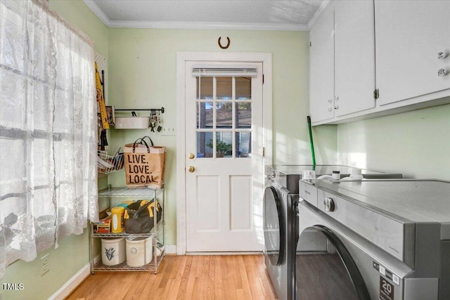 clothes washing area featuring light wood-style floors, a healthy amount of sunlight, independent washer and dryer, cabinet space, and crown molding