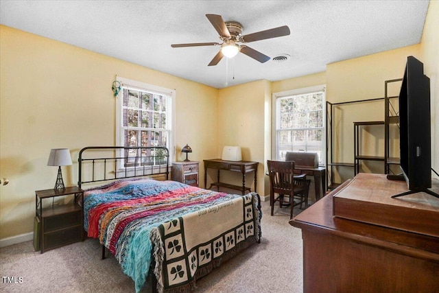 carpeted bedroom with a textured ceiling, a ceiling fan, visible vents, and baseboards