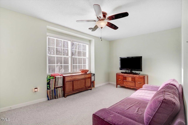 living area with baseboards, a textured ceiling, a ceiling fan, and light colored carpet