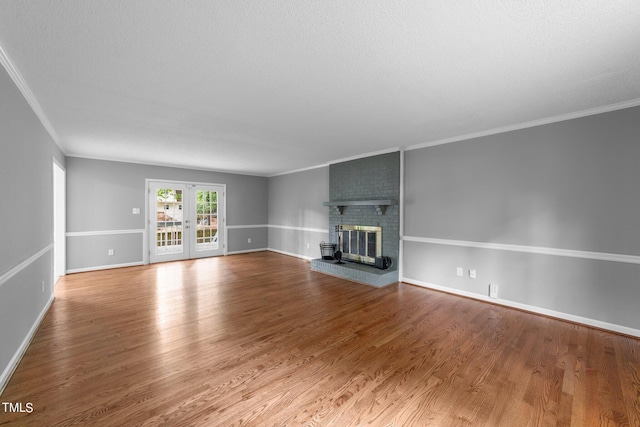 unfurnished living room featuring a fireplace, baseboards, wood finished floors, and french doors