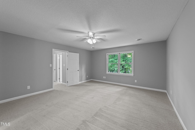 spare room featuring ceiling fan, light colored carpet, and baseboards