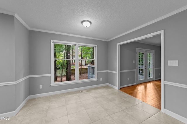 tiled empty room featuring a textured ceiling, ornamental molding, a wealth of natural light, and baseboards