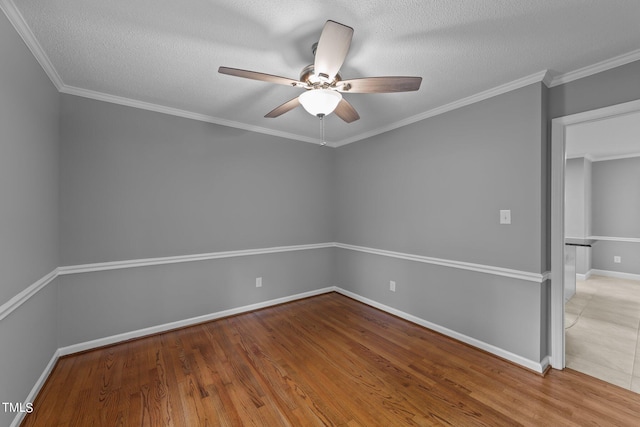 empty room featuring baseboards, a ceiling fan, ornamental molding, wood finished floors, and a textured ceiling