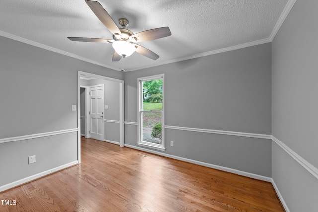 spare room featuring crown molding, a textured ceiling, baseboards, and wood finished floors