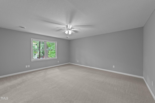 carpeted empty room featuring ceiling fan, visible vents, baseboards, and a textured ceiling