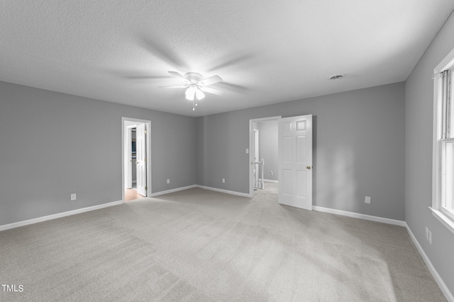 empty room with visible vents, a ceiling fan, light carpet, a textured ceiling, and baseboards