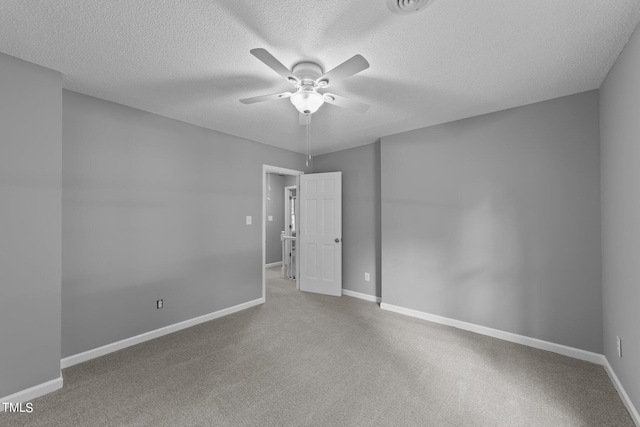 carpeted spare room with ceiling fan, a textured ceiling, and baseboards