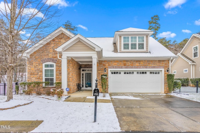 view of front of house featuring driveway, stone siding, and fence