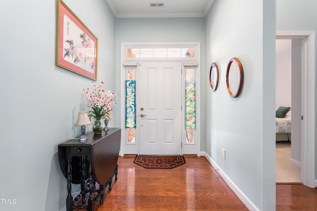 entrance foyer featuring ornamental molding, wood finished floors, and baseboards