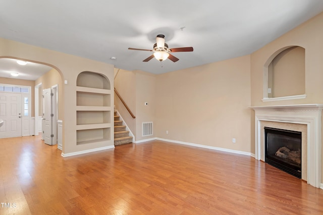 unfurnished living room featuring visible vents, stairway, built in features, light wood-type flooring, and a fireplace