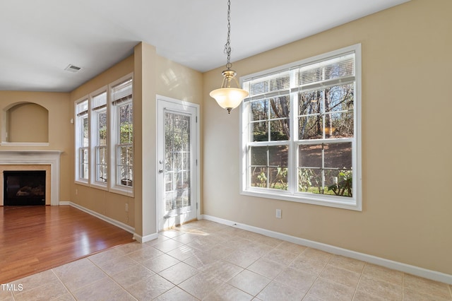 unfurnished dining area featuring tile patterned flooring, a fireplace, visible vents, and baseboards