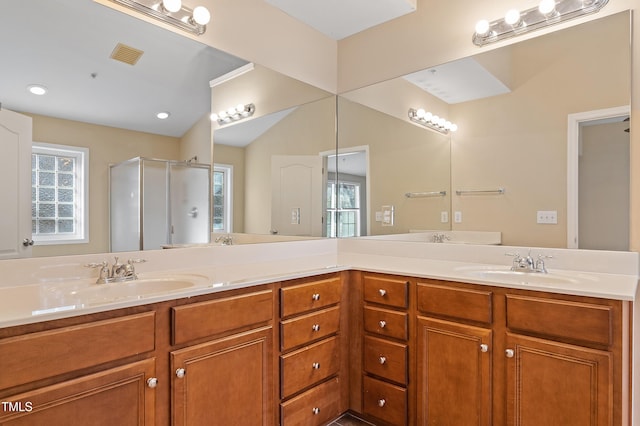 bathroom featuring double vanity, visible vents, a shower stall, and a sink