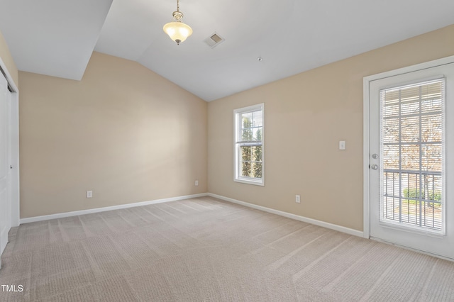 spare room featuring light carpet, plenty of natural light, baseboards, and vaulted ceiling