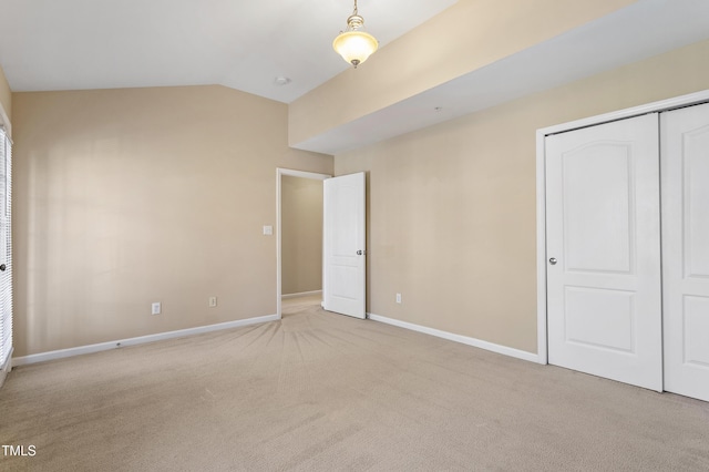 unfurnished bedroom with baseboards, lofted ceiling, carpet floors, and a closet